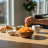 Asia Trade naturally dried pitted apricots in a wooden bowl on a sunny breakfast table with yogurt and a croissant.