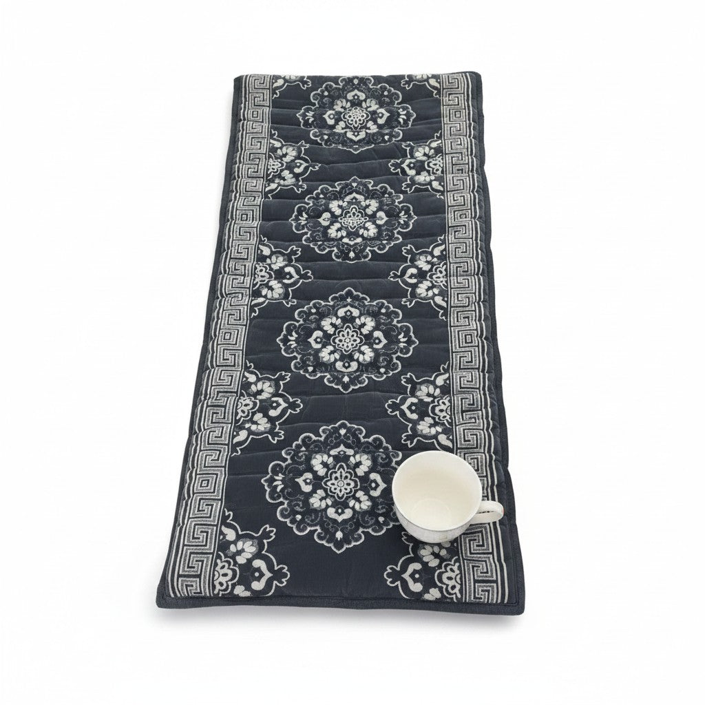 Asia Trade grey velvet Uzbek Korpacha mattress with traditional floral patterns and a white tea cup on white background