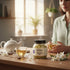 Asia Trade jasmine tea jar on a wooden table with a woman holding a warm cup of tea in a sunlit kitchen