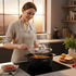 Asia Trade Kukmara 4L cast aluminum induction roaster with marble coating and glass lid, used by a woman in kitchen.