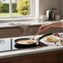 Asia Trade Kukmara 22cm marble induction pancake pan with non-stick coating on a stovetop with a crepe being cooked.