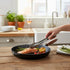 Asia Trade Siton 26cm round cast iron grill pan with ribbed surface cooking salmon and asparagus on a wooden table