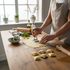 Asia Trade 4cm square ravioli stamp with wooden handle and aluminum cutter, used to shape fresh pasta on a table.